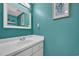 Powder room with a white vanity, large mirror, neutral fixtures, and turquoise walls at 1360 Turkey Ridge Rd. # A, Surfside Beach, SC 29575