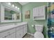 Bathroom with green walls, white vanity and cabinet and vanity mirror with modern lighting at 1360 Turkey Ridge Rd. # A, Surfside Beach, SC 29575