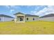 Home's backyard with green grass and rear exterior of the home with a covered porch at 1372 Palm Springs Paloma Dr, Longs, SC 29568