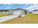 Lovely light green home featuring a white garage door, complemented by a well-maintained lawn at 1372 Palm Springs Paloma Dr, Longs, SC 29568