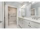 Bathroom featuring a double sink, white marble countertop, large mirror, and walk-in shower at 1435 Saint Thomas Circle # E-1, Myrtle Beach, SC 29577