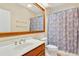 Bathroom featuring a large mirror, single sink vanity, tile floors, and tub/shower with floral curtain at 154 Windsor Circle Sw, Ocean Isle Beach, NC 28469