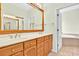 Bathroom with double vanity, ample counter space, wood cabinets, and soaking tub behind an open door at 154 Windsor Circle Sw, Ocean Isle Beach, NC 28469