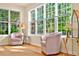 Light-filled sunroom with hardwood floors, comfortable chairs, and large windows overlooking the greenery at 154 Windsor Circle Sw, Ocean Isle Beach, NC 28469