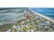 An aerial view of a coastal neighborhood featuring apartment complexes near a beach and waterway, surrounded by lush greenery at 1582 S Waccamaw Dr. # 34, Garden City Beach, SC 29576