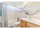 Bright bathroom featuring a wooden vanity, round mirror, and a shower-tub combo at 1614 Cottage Cove Circle, North Myrtle Beach, SC 29582