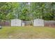 Two storage sheds with neutral coloring located on a grassy lot near a wooden fence at 1894 Athens Dr., Conway, SC 29526
