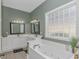 Bathroom showcasing a soaking tub, double vanity sinks, a block window, and neutral decor at 212 Greenwich Dr., Conway, SC 29526