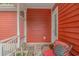 An open-air porch offers a cozy space with outdoor furniture and decorative accents, alongside the red exterior at 212 Greenwich Dr., Conway, SC 29526