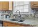 Close-up of the kitchen sink area with granite countertops and a stylish tile backsplash at 212 Sweetbay Magnolia St., Loris, SC 29569