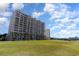 Exterior of a waterfront condo building with multiple floors of balconies and manicured green space at 2151 Bridge Ct. # 1-305, North Myrtle Beach, SC 29582