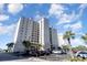 Exterior view of a high-rise condo building with multiple balconies, lush palm trees, and parking area at 2151 Bridge Ct. # 1-305, North Myrtle Beach, SC 29582