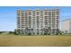 Exterior of a luxury condo building featuring multiple balconies and an expansive green space at 2151 Bridge Ct. # 1-305, North Myrtle Beach, SC 29582