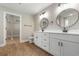 Bathroom featuring dual sinks, white cabinetry, wood floors, and entry to walk-in closet at 2260 Pearl Rd., Galivants Ferry, SC 29544