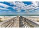 Scenic beach view with a wooden walkway leading to the ocean, offering a tranquil and accessible path to the sandy shores at 24 Frigate Ct., Pawleys Island, SC 29585
