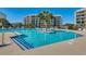 Inviting pool area with palm trees, lounge chairs, and a beautiful view of the condo building and clear blue sky at 24 Frigate Ct., Pawleys Island, SC 29585