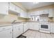 Bright kitchen featuring white cabinets, a double sink, tile floors, and essential appliances at 2511 S Ocean Blvd. S # 1802B, Myrtle Beach, SC 29577