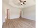 Expansive bedroom featuring a tray ceiling, fan, light wood flooring, and ensuite bath at 268 Stillbrook Dr., Longs, SC 29568