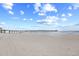 Expansive beach view with a long pier extending into the ocean under a bright, cloud-filled sky at 3401 N Ocean Blvd. # 309, North Myrtle Beach, SC 29582