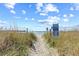 Sandy walkway leads to the beach and ocean under a blue sky with scattered clouds and tall grassy dunes at 3401 N Ocean Blvd. # 309, North Myrtle Beach, SC 29582