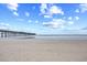 View of sandy beach on a clear day with a pier in the distance under a blue sky with scattered clouds at 3401 N Ocean Blvd. # 309, North Myrtle Beach, SC 29582