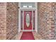 Close-up of a decorative red front door with glass panels and brick surround at 372 Waterfall Circle, Little River, SC 29566