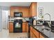 Well-appointed kitchen with stainless steel sink, sleek black appliances, and modern backsplash at 424 Enderby Way, Little River, SC 29566