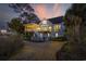 The charming home's exterior is illuminated against a vibrant sunset backdrop, showcasing the spacious yard and deck at 4616 Eyerly St., North Myrtle Beach, SC 29582