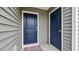 A well-lit entryway showcases gray siding and a vibrant blue front door at 478 Samara Dr., Longs, SC 29568