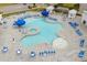 Aerial view of a uniquely shaped pool with lounge chairs and tables with blue umbrellas throughout the pool deck area at 5068 Wavering Place Loop, Myrtle Beach, SC 29579