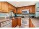 Compact kitchen with wood cabinets and white appliances, including a dishwasher, range, and microwave at 5511 North Ocean Blvd. # 806, Myrtle Beach, SC 29577