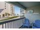 Relaxing balcony with blue chairs offering views of the ocean and lush landscaping at 6000 N Ocean Blvd. # 133, North Myrtle Beach, SC 29582