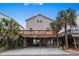 Coastal home with a large deck, street-level parking, and stairs leading to the elevated living space at 6001 - B7 S Kings Hwy., Myrtle Beach, SC 29575