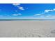 Serene beach with soft sand and calm ocean waves under a bright blue sky with scattered clouds at 625 N Waccamaw Dr. # 107, Murrells Inlet, SC 29576