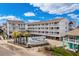 Three-story condo building with a community pool, palm trees and ample parking at 625 N Waccamaw Dr. # 107, Murrells Inlet, SC 29576