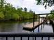 Scenic view of a wooden dock on the water surrounded by lush trees and a bridge at 630 Heartwood Dr., Conway, SC 29526