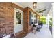 Inviting brick porch with a ceiling fan, white pillars, and comfortable seating at 672 Ashley Manor Dr., Longs, SC 29568