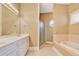 Bathroom with dual sinks, a soaking tub, and a separate shower with gold finishings at 79 Windsor Circle Sw, Ocean Isle Beach, NC 28469