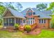 Back exterior featuring brick, shingles, screened in porch, deck with stairs, and lawn with landscaping at 79 Windsor Circle Sw, Ocean Isle Beach, NC 28469