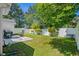 Green backyard with a concrete patio and rocking chairs, set against a backdrop of mature trees and privacy fencing at 9607 Kings Grant Dr., Murrells Inlet, SC 29576