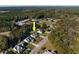 Aerial view of a home nestled in a wooded neighborhood, highlighted by a bright yellow arrow at 100 Woodlyn Ave., Little River, SC 29566