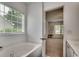 Bright bathroom featuring a soaking tub and an open doorway to an adjacent living area at 100 Woodlyn Ave., Little River, SC 29566