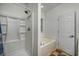 Well-lit bathroom featuring a shower, a separate bathtub, and a window at 100 Woodlyn Ave., Little River, SC 29566
