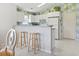 Efficient kitchen with white cabinets, appliances, breakfast bar, and decorative pineapple wallpaper at 10106 Duval Dr., Murrells Inlet, SC 29576
