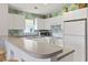 Kitchen area with white cabinets, appliances, countertop bar, and decorative pineapple wallpaper at 10106 Duval Dr., Murrells Inlet, SC 29576