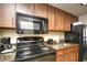 Cozy kitchenette featuring a microwave, stove, and sink with granite countertop and wood cabinets at 1105 S Ocean Blvd. # 1144, Myrtle Beach, SC 29577