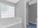 Bright bathroom featuring a soaking tub and a glass block window at 125 Balsa Dr., Longs, SC 29568