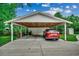 Carport showcasing a red car inside, surrounded by lush green trees and shrubbery at 1261 Parkhill Dr., Conway, SC 29526