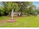 Landscaped front yard featuring a palm tree, green grass, and a charming brick home in the background at 127 Pinfeather Trail, Myrtle Beach, SC 29588