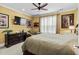 A comfortable bedroom with a ceiling fan, TV, warm yellow walls, and tasteful decor at 1763 Hemingway Rd., Loris, SC 29569